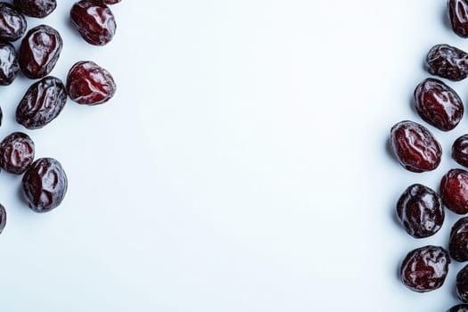 A collection of raisins is artfully arranged on a clean, solid white surface. The dark, wrinkled fruit contrasts beautifully against the bright background, showcasing their natural texture and color.