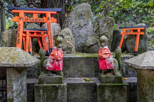 stone Inari fox statues  torii gates at the entrance of a japanese shrine