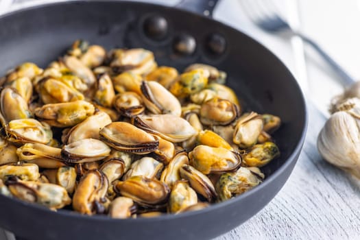 Shelled mussels meat in pan on a white table
