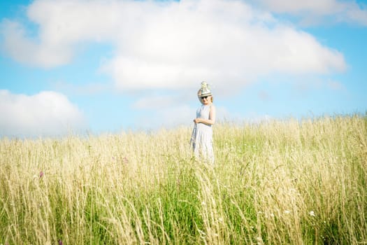 Happy mature woman with wildflowers in a tall grass field on a bright summer day.