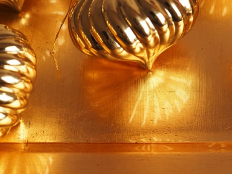 Close up of golden Christmas baubles on a shiny golden background with space for your text