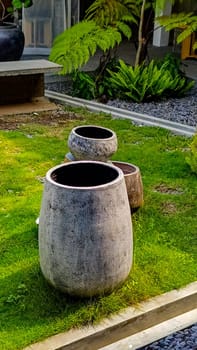 A vibrant outdoor scene featuring four decorative garden pots of various textures and colors, placed on a well-maintained lawn.