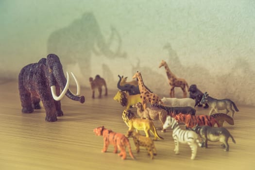 A vibrant and colorful arrangement of charming toy animals beautifully surrounding a woolly mammoth figure