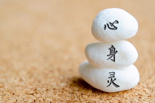 Mind, Body and Spirit text in Chinese character on white stones. Meditation and peace concept.