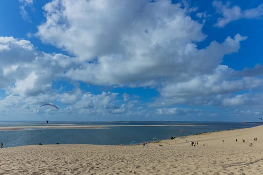 Dune of Pilat, France - August 14, 2024: People paragliding at the Great Dune of Pilat, Arcachon Basin, Nouvelle Aquitaine, France.