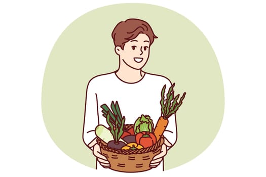 Man with basket of vegetables smiles and recommends going vegan or eating organic raw food. Vegetarian guy offers to buy farm vegetables and start new healthy diet to improve health