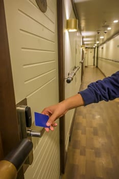 A hand holding a blue card key near a hotel door lock in a long hallway, key electronic lock, hotel room, holidays in mallorca, spain