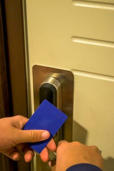 A hand holding a blue card key close to a hotel door lock, key electronic lock, hotel room, holidays in mallorca, spain