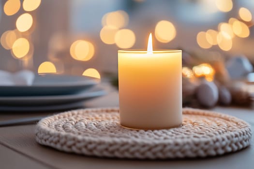 A lit candle rests on a woven mat, casting a gentle glow over a beautifully set dinner table with soft lighting.