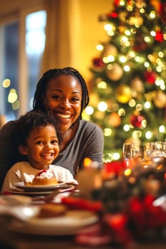 A mother and her young child enjoy a festive holiday meal, smiling together beside a beautifully lit Christmas tree.
