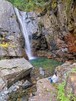 A woman sitting close to the stream enjoys the view of Char Falls in north Idaho.