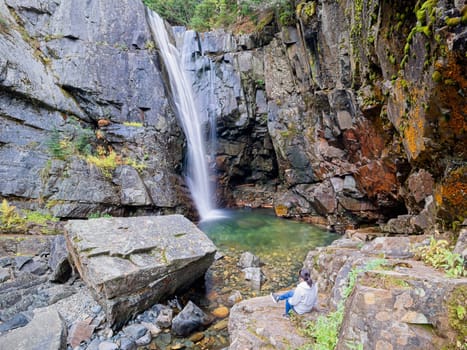 A woman sitting close to the stream enjoys the view of Char Falls in north Idaho.