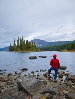 A woman stands by the rocky shore of Lake Wenatchee on a cloudy morning in central Washington.