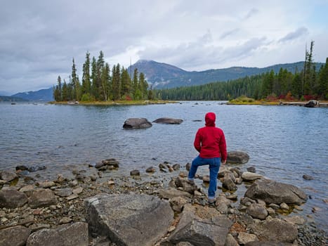 A woman stands by the rocky shore of Lake Wenatchee on a cloudy morning in central Washington.
