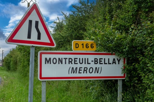 A sign with the word Montreuil-Bellay on it. The sign is yellow and red