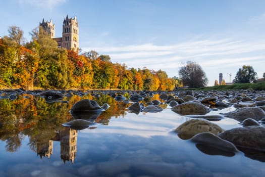 St. Maximilian's Church reflected in the Isar River in autumn in Munich, Bavaria, Germany