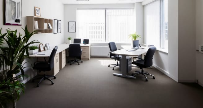 Spacious modern office with multiple desks, chairs, and potted plants. Natural light floods the room through large windows, creating a bright and productive workspace.