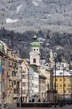 Innsbruck, Austria - August 4, 2022: View of the Alte Spitalskirche (Hospital Church of the Holy Spirit) bell tower and Column of St. Anna on Maria Theresa Street