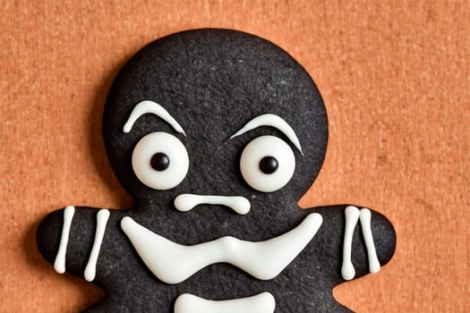 Angry gingerbread skeleton cookie on orange background.