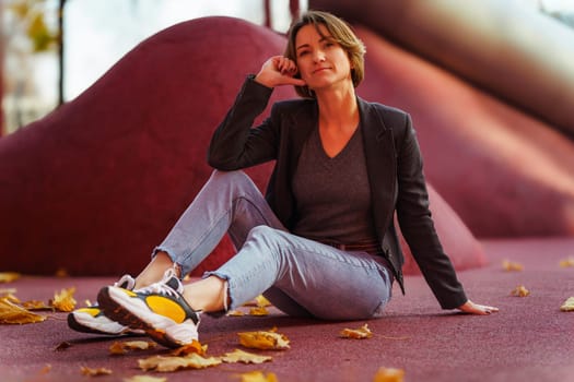 Young woman enjoying autumn leaves on red background.