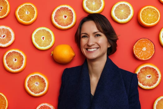 smiling young woman in dark blue coat with citrus background.