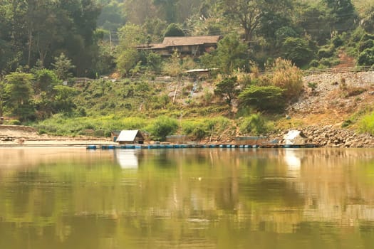 View from the slow boat from Thailand to Laos onto the shore of the Mekong River with a aquaculture installation, Laos 2023