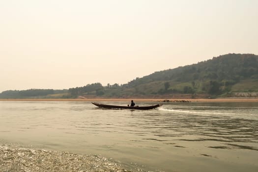 View from the slow boat from Thailand to Laos onto a small boat with two locals on the Mekong River, Laos 2023