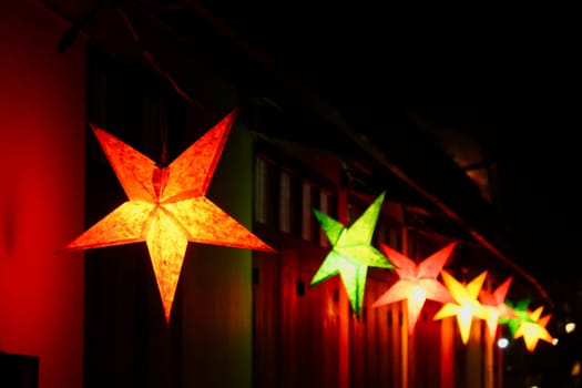 Many colorful star shaped lanterns illuminate a street in the old town of Luang Prabang at night, Laos 2023