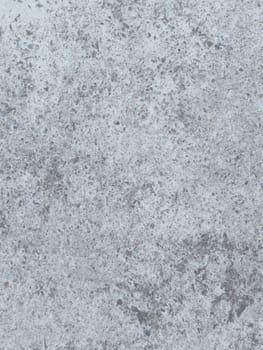 A grey and white wall with a few spots of color. The wall is made of concrete and has a rough texture
