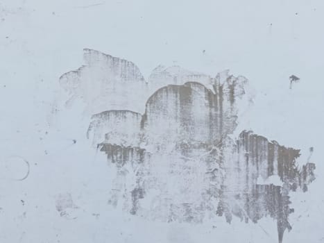 A grey and white wall with a few spots of color. The wall is made of concrete and has a rough texture
