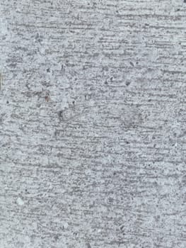 A grey and white wall with a few spots of color. The wall is made of concrete and has a rough texture