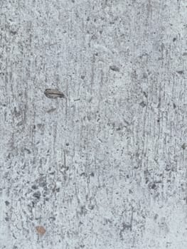 A grey and white wall with a few spots of color. The wall is made of concrete and has a rough texture