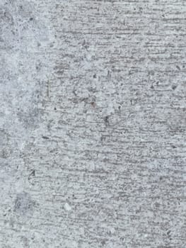 A grey and white wall with a few spots of color. The wall is made of concrete and has a rough texture