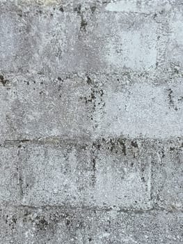 A grey and white wall with a few spots of color. The wall is made of concrete and has a rough texture