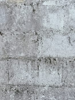 A grey and white wall with a few spots of color. The wall is made of concrete and has a rough texture
