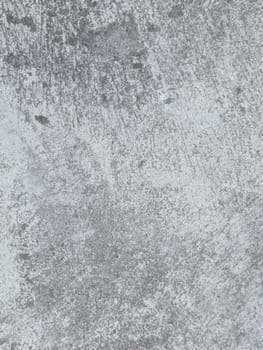 A grey and white wall with a few spots of color. The wall is made of concrete and has a rough texture