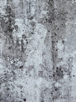 A grey and white wall with a few spots of color. The wall is made of concrete and has a rough texture
