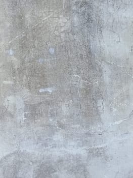 A grey and white wall with a few spots of color. The wall is made of concrete and has a rough texture