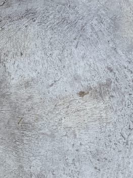 A grey and white wall with a few spots of color. The wall is made of concrete and has a rough texture