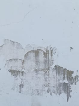 A grey and white wall with a few spots of color. The wall is made of concrete and has a rough texture