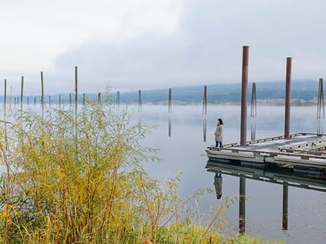 A landscape photo of a woman standing on a dock looking out at the calm water of the Pend Oreille River in eastern Washington.