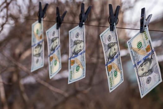 hundred-dollar bills hanging on a clothesline, secured with clothespins, symbolizing money laundering or financial dealings
