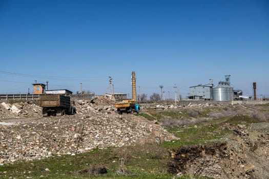 two old soviet trucks driving stones along concrete rubble trough Industrial area at sunny day