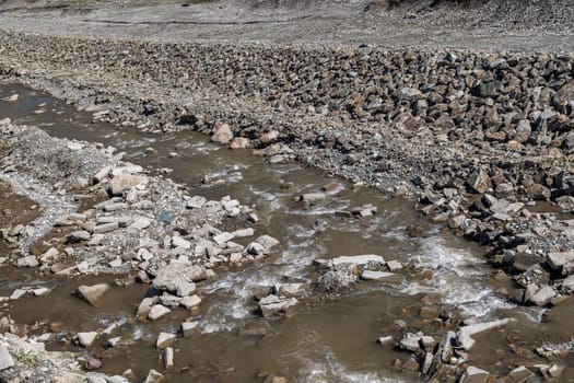 shallow river canal reinforced with large stone embankments at sunny day