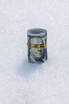A roll of real cash standing on a snow surface at sunny winter day.