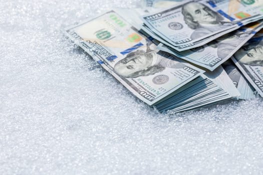 A bundle of cash lying on a snow surface at sunny winter day