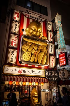 Golden  doll holding kushikatsu skewers in shinsekai, osaka