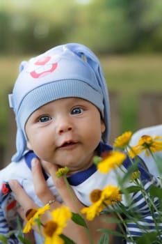 A joyful little baby is happily surrounded by beautiful and vibrant flowers in a sunny outdoor environment