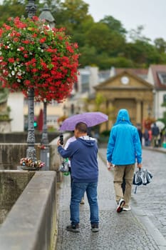 Asian tourist taking pictures of sights on the Old Main Bridge, alte Mainbrücke in Wurzburg in Germany in the rain