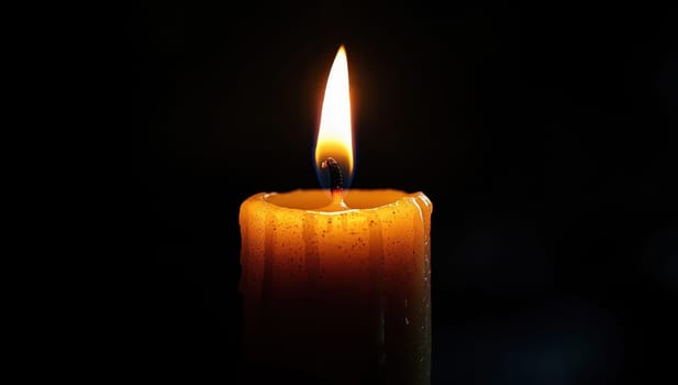 A lit candle against a dark background. Concept of light, warmth, and tranquility.